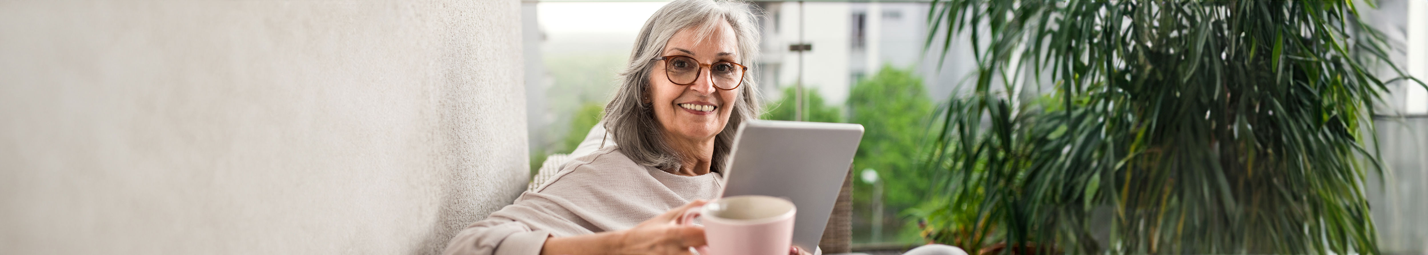 Happy elderly woman smiling and holding a cup.