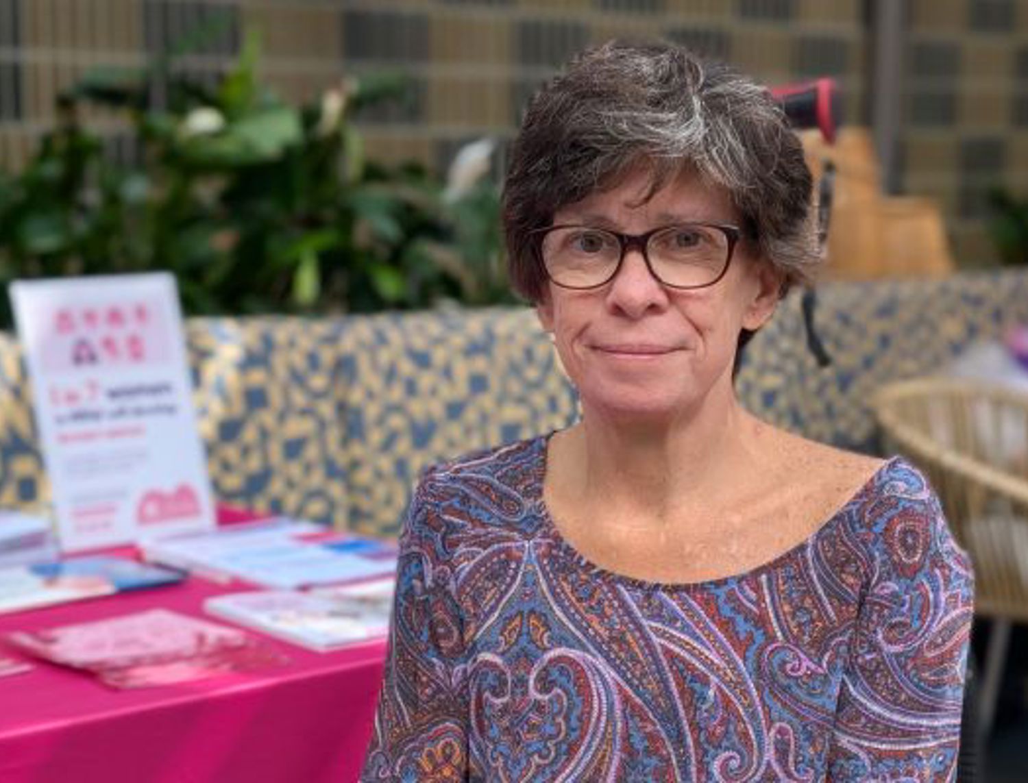 woman with glasses sitting at a table with a pink tablecloth